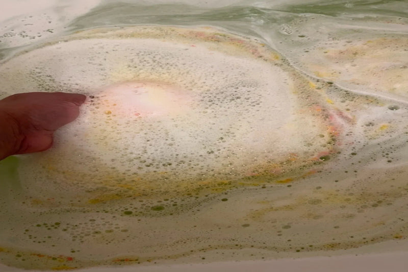 Bath bomb fizzing and foaming in water creating a colorful bath soak that is scented